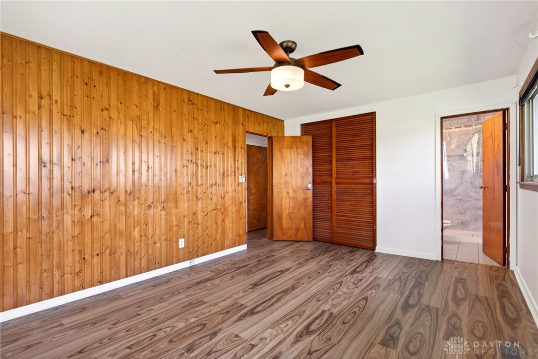 1005 Free Road New Carlisle, OH 45344 - Photo 20 of 43 This spacious bedroom features wood paneling and elegant wood flooring, with a ceiling fan for comfort.