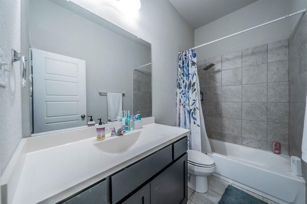 1885 Arbor Drive Forney, TX 75126 - Photo 12 of 33 Full bathroom featuring shower / tub combo with curtain, vanity, light tile patterned flooring, and a textured wall