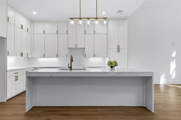 a kitchen with stainless steel appliances granite countertop a sink a stove and white cabinets with wooden floor
