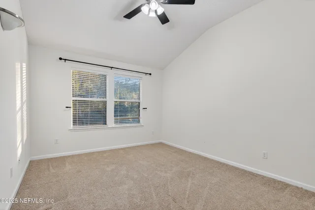 an empty room with a window and a ceiling fan
