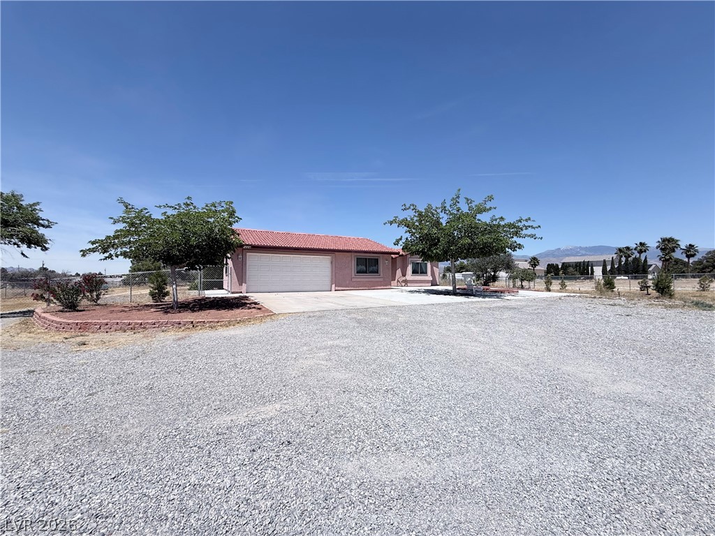 1220 East Gamebird Road Pahrump, NV 89048 - Photo 33 of 49 Discover a charming residence with a red tile roof, complemented by a wide gravel driveway and mature trees.
