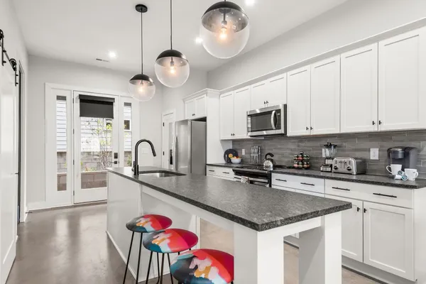 a kitchen with stainless steel appliances granite countertop a stove top oven a sink dishwasher a dining table and chairs with wooden floor