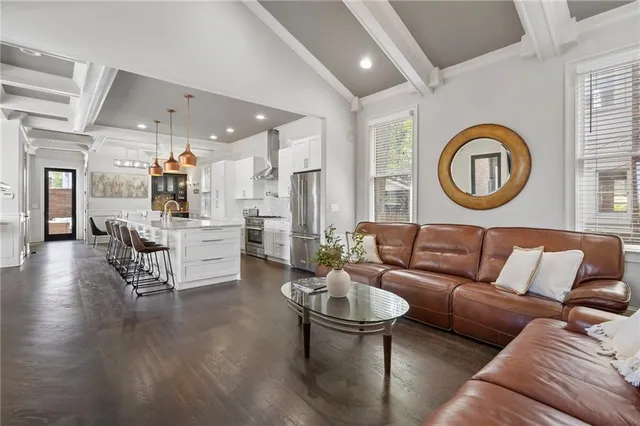 a kitchen with stainless steel appliances kitchen island granite countertop a refrigerator a stove a dining table and chairs with wooden floor