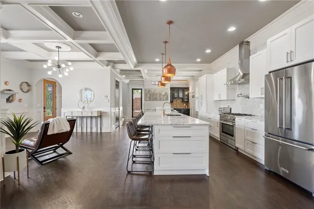 a kitchen with stainless steel appliances kitchen island granite countertop a table chairs and a refrigerator