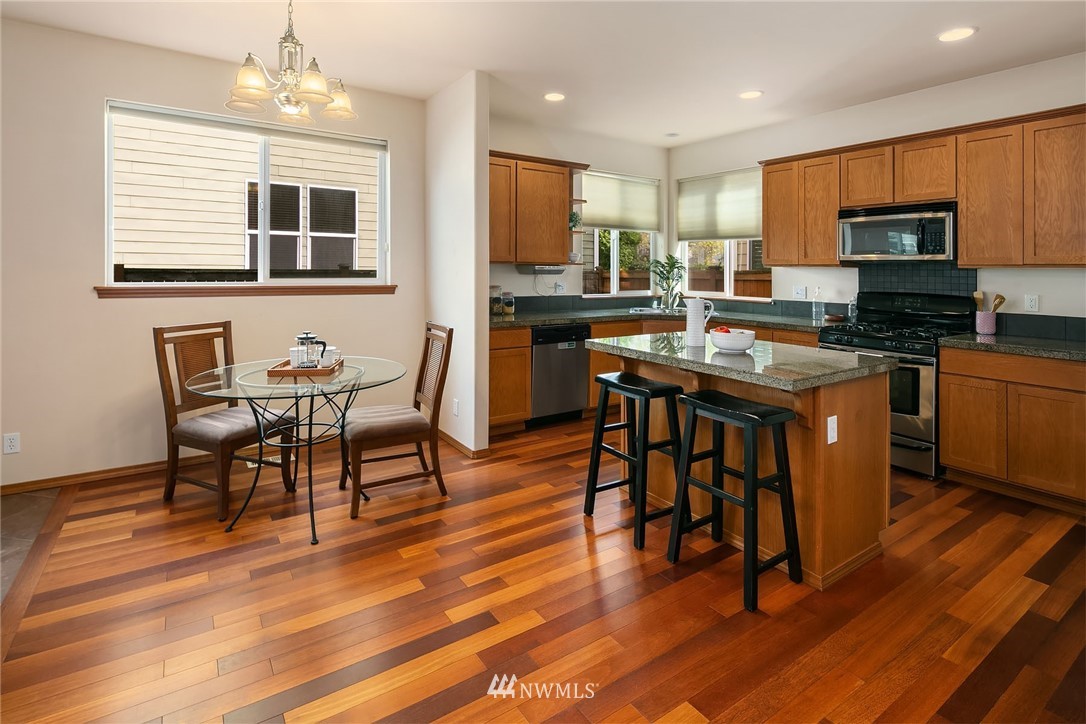3425 183rd Place Southeast Bothell, WA 98012 - Photo 12 of 25 a kitchen with stainless steel appliances granite countertop a stove a refrigerator a sink a dining table and chairs with wooden floor