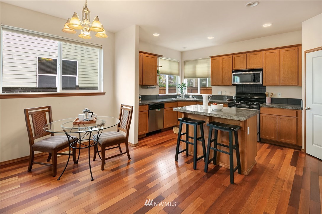 3425 183rd Place Southeast Bothell, WA 98012 - Photo 8 of 25 a kitchen with stainless steel appliances granite countertop wooden floor dining table and chairs