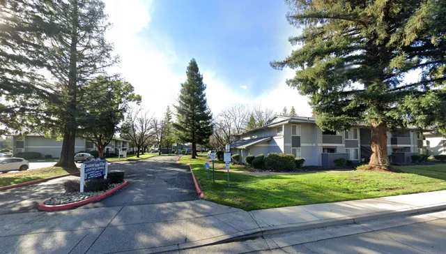 a view of a white house with a yard and large trees