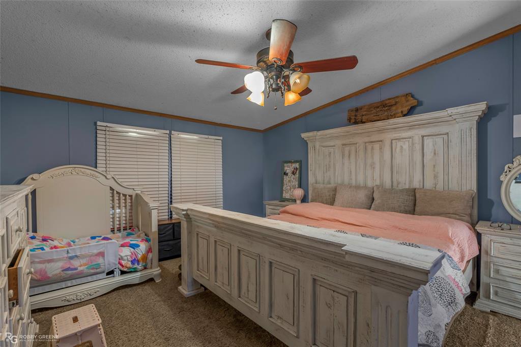 10660 Bowen Road Vivian, LA 71082 - Photo 15 of 27 a bedroom with a bed a chandelier and dresser