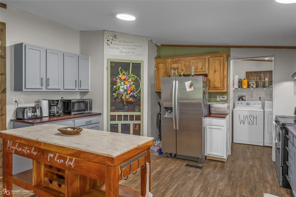 10660 Bowen Road Vivian, LA 71082 - Photo 10 of 27 a kitchen with stainless steel appliances granite countertop a refrigerator a sink dishwasher and white cabinets with wooden floor