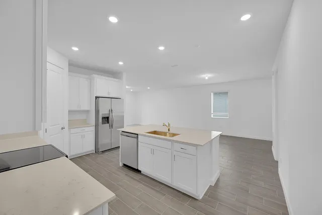 a kitchen with a sink a refrigerator and cabinets