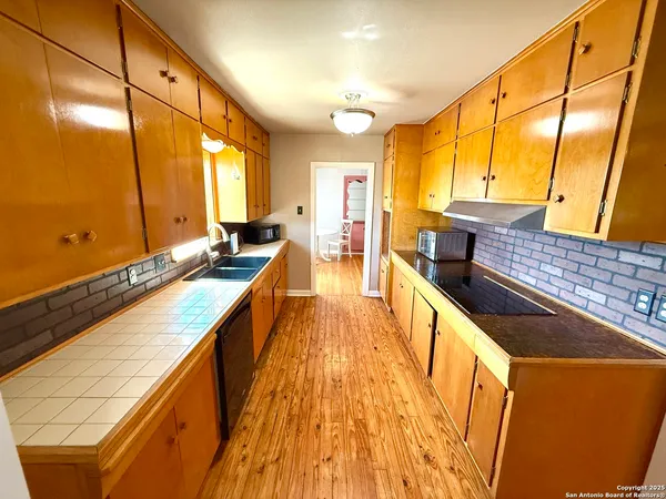 a large kitchen with lots of counter top space and wooden floor