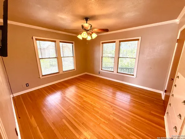a view of an empty room with wooden floor and a window