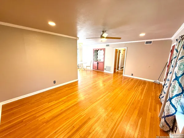 a view of an empty room with window and wooden floor