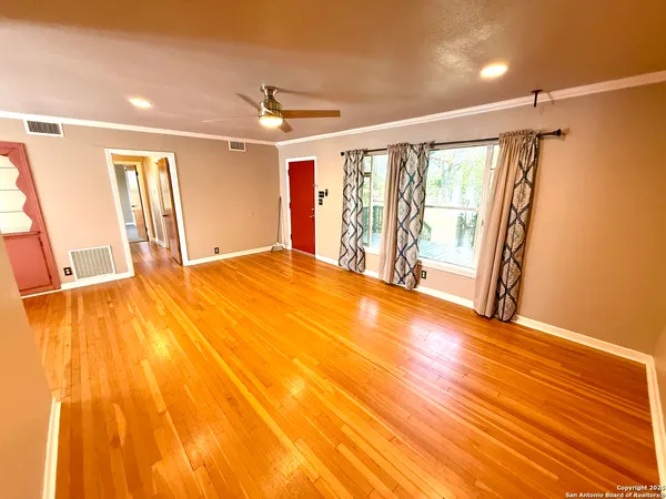 a view of an empty room with wooden floor and a window