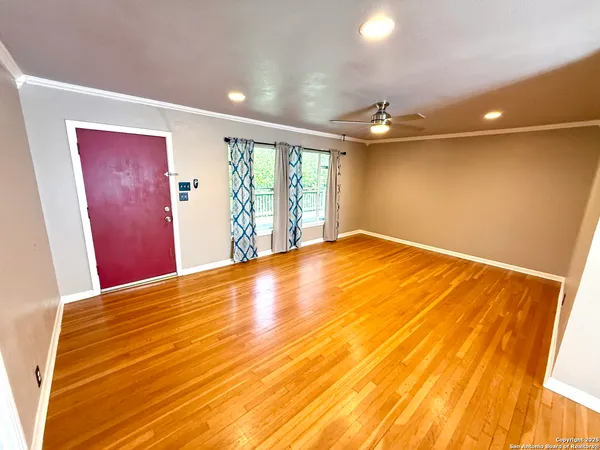 a view of empty room with wooden floor and fan