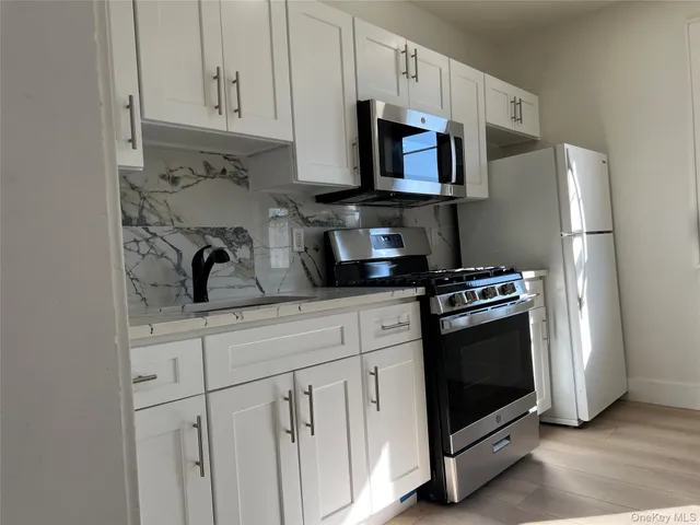 a kitchen with stainless steel appliances granite countertop a refrigerator stove a sink and dishwasher with white cabinets