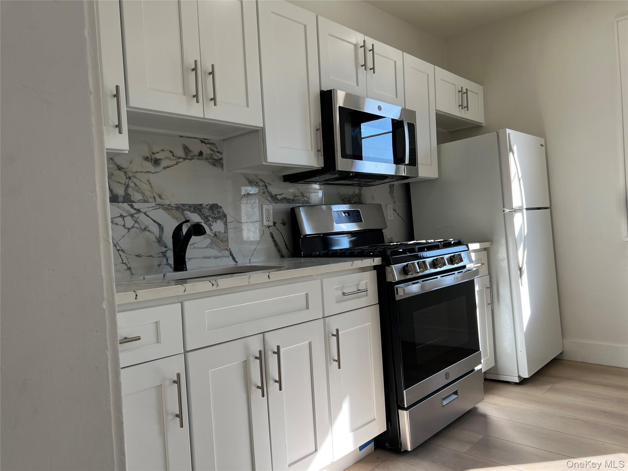 a kitchen with stainless steel appliances granite countertop a refrigerator stove a sink and dishwasher with white cabinets