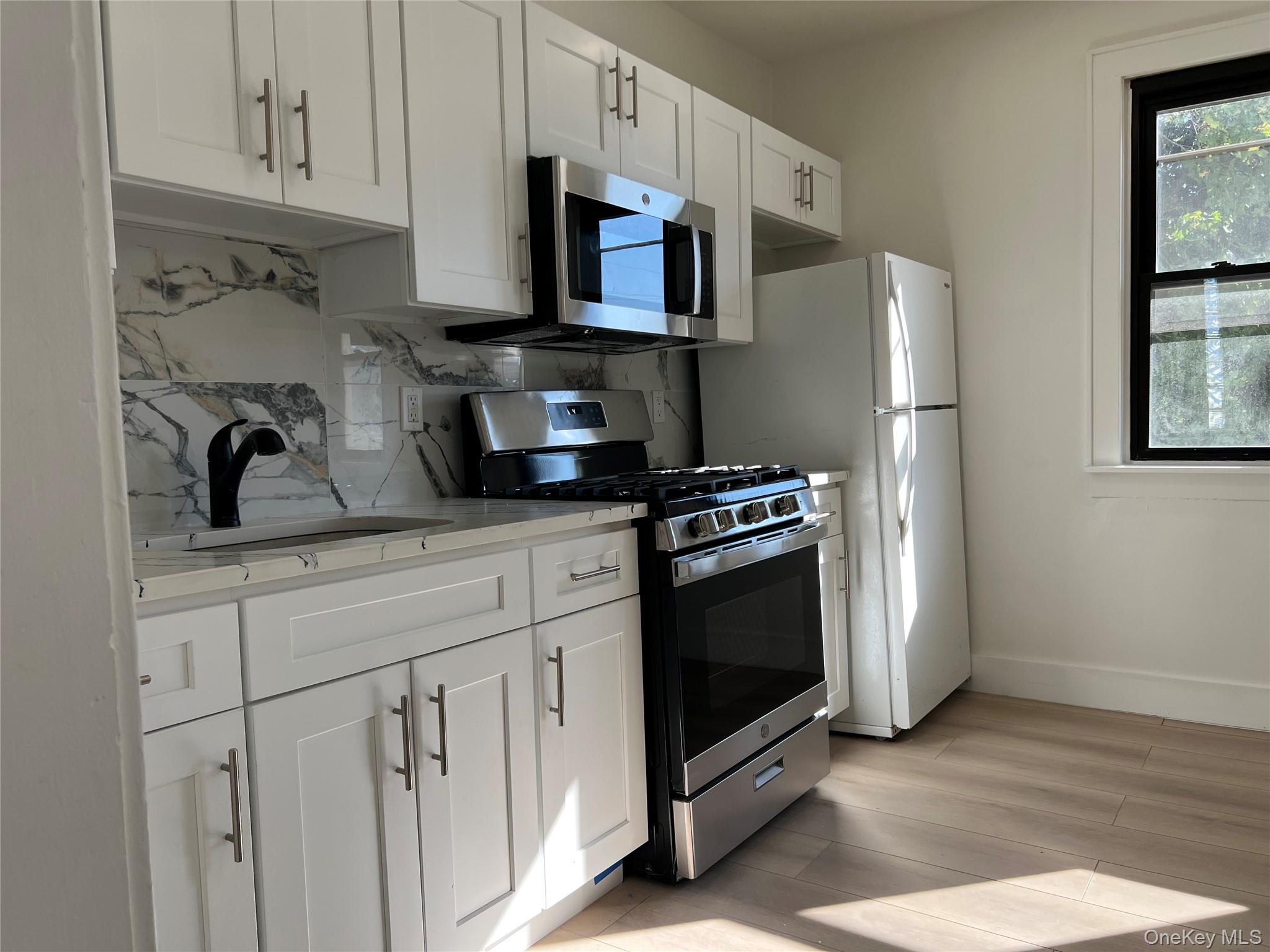 28 Walt Whitman Road Huntington Station, NY 11746 - Photo 9 of 17 a kitchen with stainless steel appliances a stove a microwave and a refrigerator