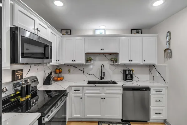 a kitchen with white cabinets and appliances