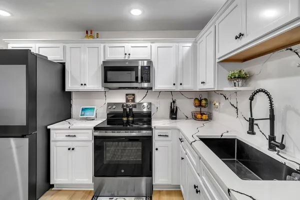 a kitchen with a sink white cabinets and stainless steel appliances