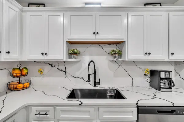 a kitchen with white cabinets and sink