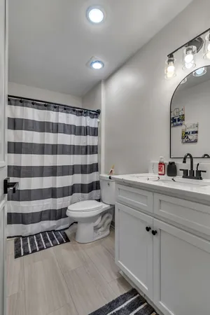 a bathroom with a sink a toilet a large mirror and shower curtain