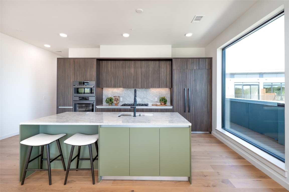 2209 South 1st Street, Unit 407 Austin, TX 78704 - Photo 7 of 30 a kitchen with kitchen island a sink table and chairs