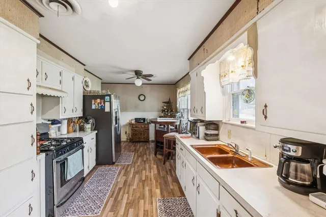 a kitchen with stainless steel appliances a stove a sink dishwasher a refrigerator white cabinets and wooden floor