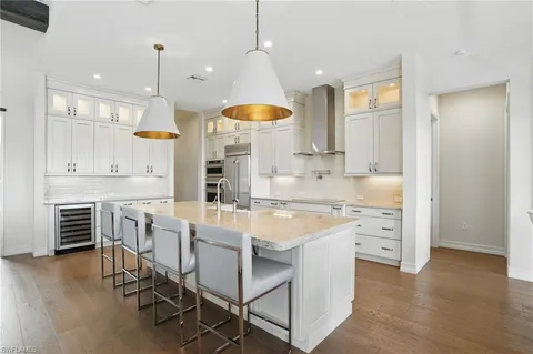 a kitchen with a table chairs stove a sink dishwasher and a refrigerator with wooden floor