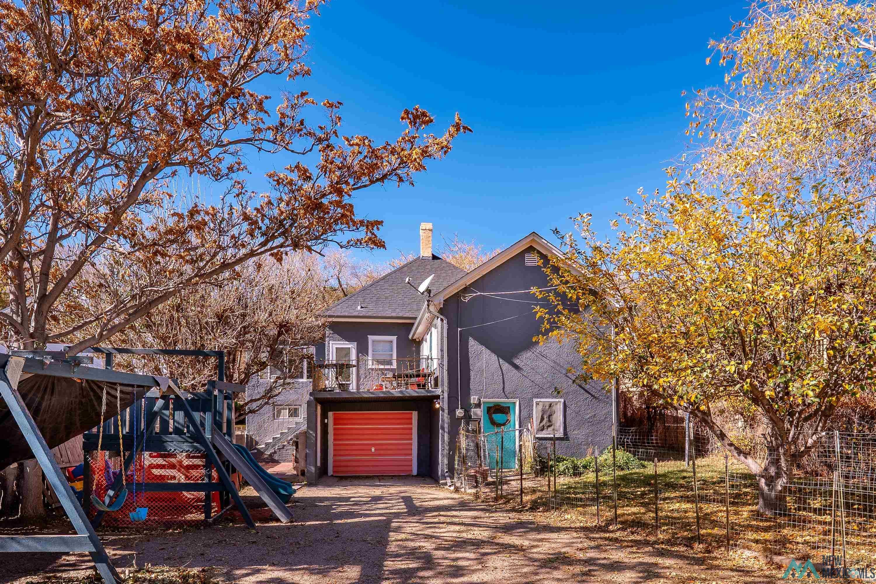 727 South 6th Street Raton, NM 87740 - Photo 35 of 47 Back of property featuring dirt driveway, a chimney, a playground, a garage, and stucco siding