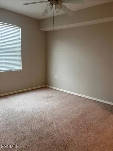 an empty room with a window and a fan