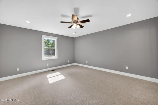 an empty room with windows and fan