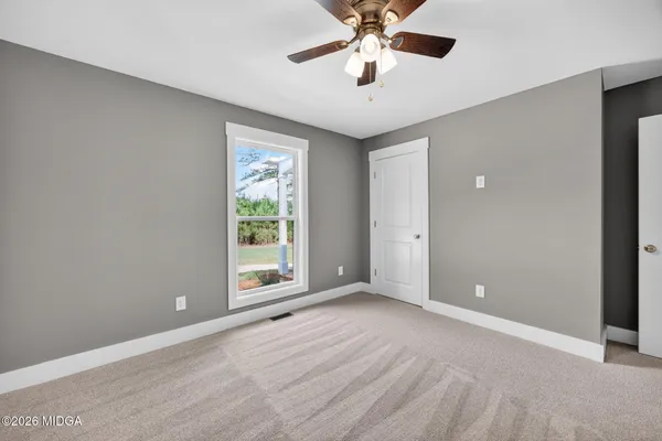 an empty room with windows and fan