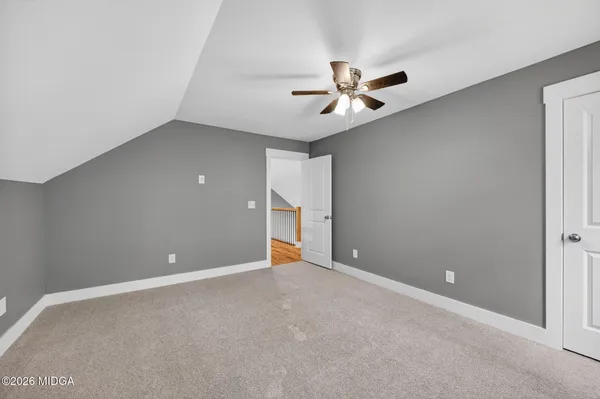 an empty room with closet and a ceiling fan