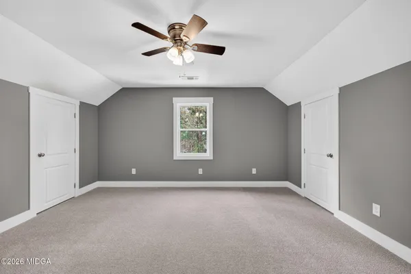 an empty room with windows and fan