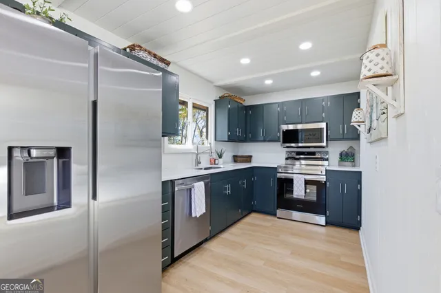 a large kitchen with stainless steel appliances kitchen island granite countertop a refrigerator and a sink