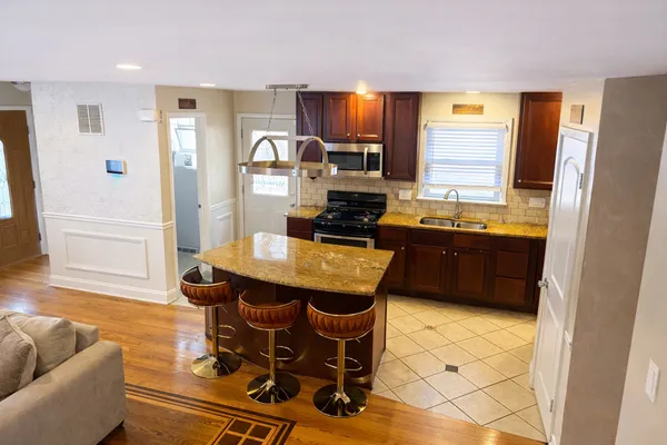 a kitchen with granite countertop a sink a stove a refrigerator a dining table and chairs