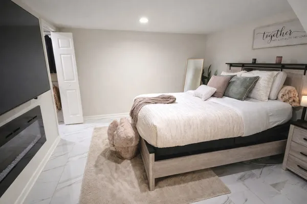 a bed sitting in a bedroom next to a window with a flat screen tv