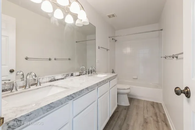 a bathroom with a granite countertop sink a toilet and shower