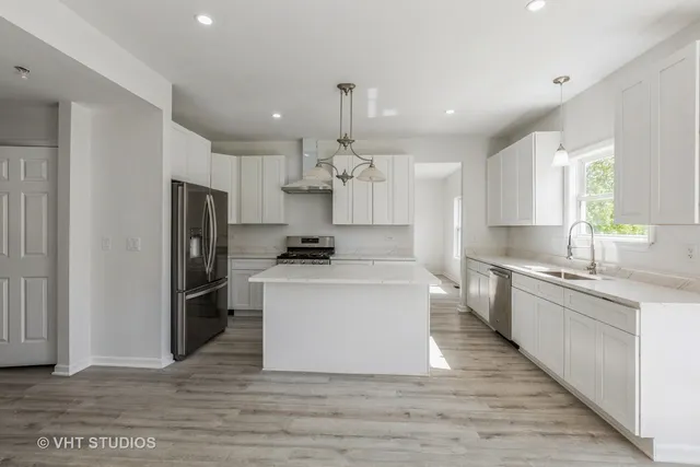 a large kitchen with stainless steel appliances a large center island attached withe living room