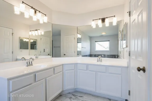a bathroom with a double vanity sink mirror and next to a window