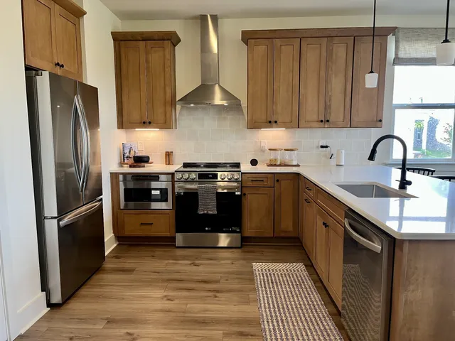 a kitchen with stainless steel appliances granite countertop a sink a stove and a wooden floors