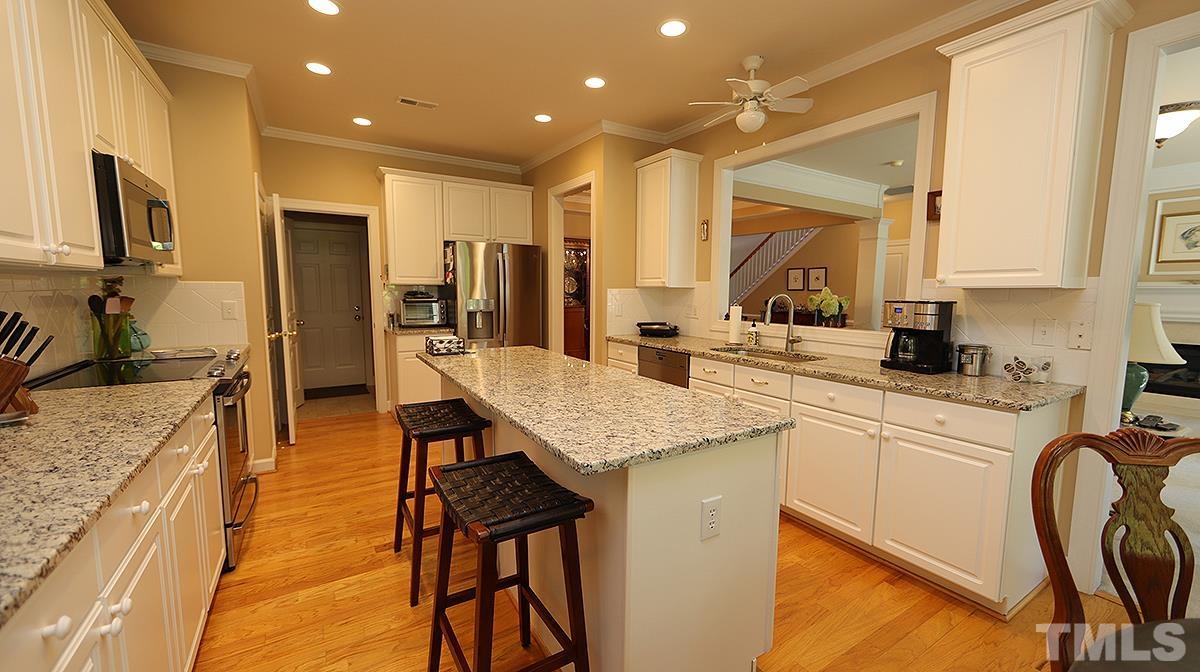 3621 Lion Ridge Court Raleigh, NC 27612 - Photo 11 of 34 a kitchen with stainless steel appliances granite countertop table chairs sink and cabinets
