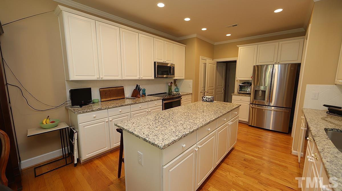 3621 Lion Ridge Court Raleigh, NC 27612 - Photo 10 of 34 a kitchen with stainless steel appliances granite countertop a refrigerator a stove and a sink with wooden floor