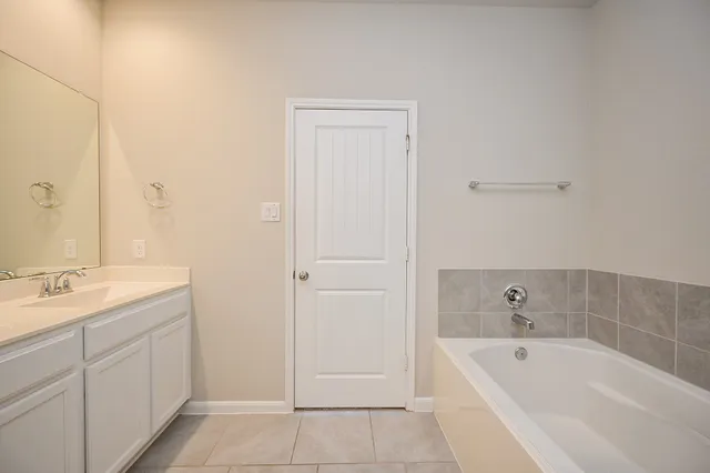 a spacious bathroom with a tub sink and mirror