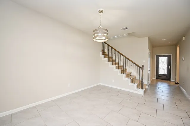 a view of a hallway with stairs and chandelier