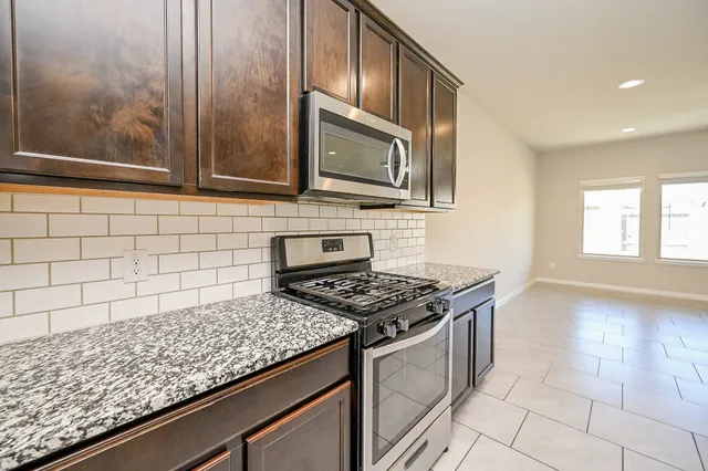 a kitchen with stainless steel appliances granite countertop a stove a sink and a microwave