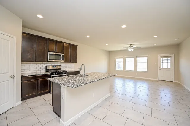 a large kitchen with stainless steel appliances granite countertop a stove top oven a sink dishwasher a dining table and chairs with wooden floor