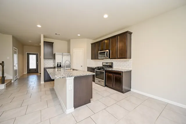 a large kitchen with stainless steel appliances a stove a sink a microwave and cabinets