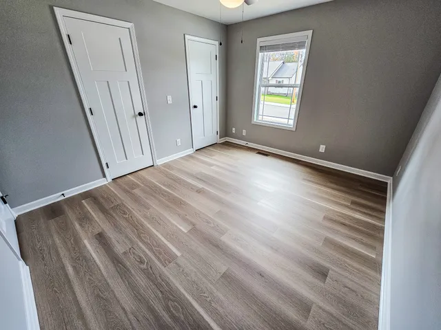 a view of an empty room with wooden floor and a window